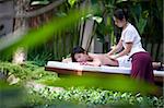 A young woman gets a massage outside in a tropical environment