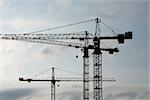 Tower crane silhouettes against cloudy sky