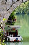 A small boat under an old stone bridge