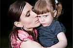 Mother Kissing Daughter Cheek. Close-Up Portrait