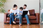 Parents and son playing together with a laptop on a couch