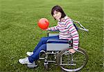 Woman in wheelchair with a red ball in hands
