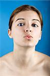 Close up portrait of a beautiful female model kissing, isolated on a blue background