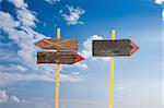 Direction signs against blue sky with white clouds