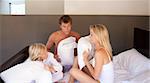 Parents and son having a pillow fight on bed