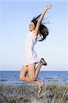 Beautiful brunette jumping in the summer blue beach