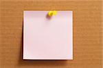 Pink sticker note with yellow push-pin on cardboard