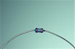 A small resistor with curved leads on a blue background.
