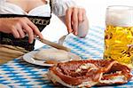 Close-up of Bavarian Girl having typical Oktoberfest meal with beer stein (Mass), sausage (Weisswurst) and Pretzel