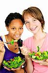 Isolated portrait of two teenage girls eating salad