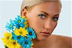 beauty portrait of pretty young blond girl with blue and yellow daisy near her face