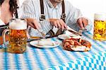 close-up of Bavarian couple having lunch at Oktoberfest with beer stein (Mass), Sausage (Weisswurst) and Pretzel (Brezn)