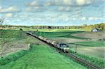 Freight train hauled by the diesel locomotive passing the fields