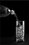 Mineral water being poured into a glass is isolated against a black background