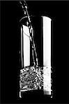Mineral water pouring into a glass is isolated against a black background