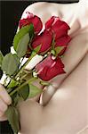 Romantic nude woman in love holding red roses in hands