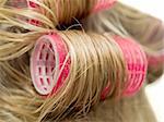 A close-up of red curlers in blond hair