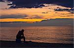 A fisherman on the beach. Fishing at sunset.