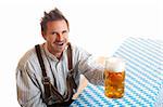 Bavarian Man dressed with traditional leather trousers (lederhosen) cheers with Oktoberfest Beer Stein in his hand.