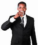Friendly African businessman drinking a glass of champagne and standing in front of the camera