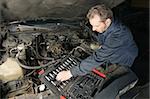 A mechanic repairing an engine of an old car.