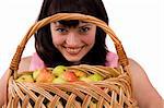 Beautiful girl holding a basket of delicious fresh fruits. Woman in pink dress is standing and holding a basket full apples on white background. Pretty girl with basket of apples. Isolated over white.