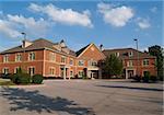 Two story red brick office building with parking spaces.