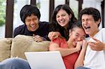 A group of multi ethnic student laughing at something on the laptop.