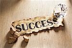 Success concept using burnt paper with word success printed on it, diamond and gold rock around it