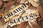 Creativity is key to success concept using words printed on burnt paper and related objects, surrounded with dry leaf