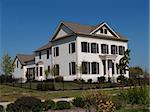 Two story new home built to look like an old historical home complete with the added on look, painted brick and a wrought  iron fence.