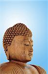 Head of a wooden buddha over blue bacground with white central glow.