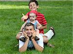two sons are sitting on their father's back holding thumbs up