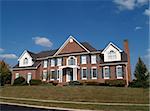 Large two story brick residential home with blue shutters and dormers.