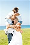 Cute young kids embracing each other as they sit up on the shoulders of parents