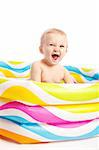 Laughing baby boy sitting in a kids rubber pool