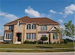 Two story contemporary stone residential home with arched windows.