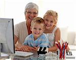 Happy children using a computer with their grandmother at home