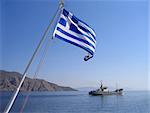 Sea view with greek flag, mountain and cargo ship