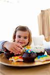 Smiling little girl looking at colorful confectionery at home