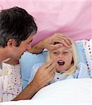 Father taking his daughter's temperature with a thermometer in bed