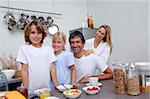 Parents and children having breakfast together in the kitchen