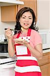Beautiful Asian woman eating eggs with a fork in the kitchen