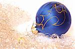 Blue Christmas ball and golden tinsel. Isolated on white