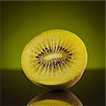 Half kiwi on green background with reflection