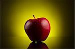 Fresh red apple on dark background with yellow gradient