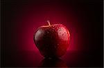 Fresh wet red apple with water drops on dark background with red gradient