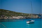 Boats moored in the crystal clear waters of the Blue Lagoon on the island of Comino in Malta.