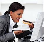 Close-up of a laughing businesswoman eating a chocolate eclair in the office