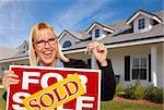 Beautiful Female Holding Keys to a New House & Sold Real Estate Sign.